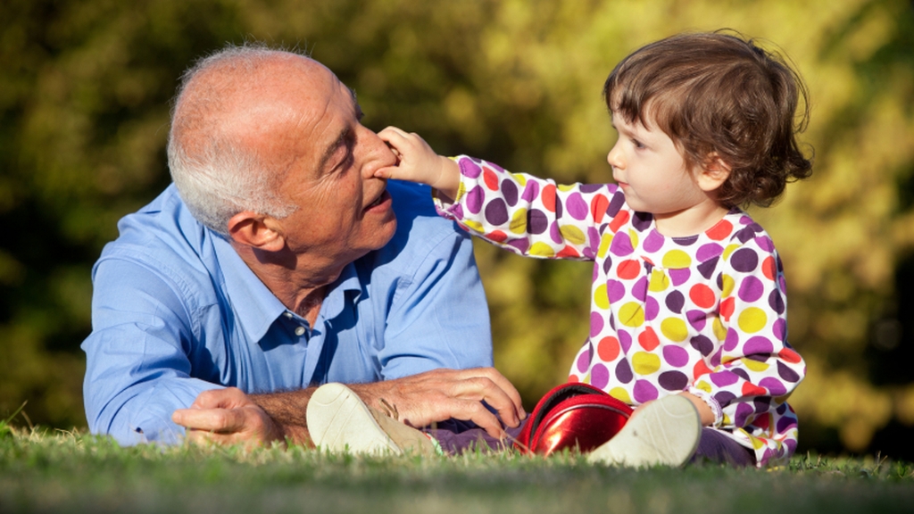 Un adulte et un enfant jouent dans l’herbe, en illustration de l’appel aux dons.