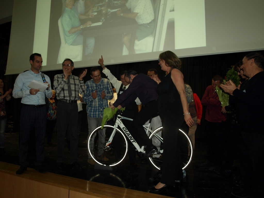 Participants applaudissant autour du vélo présenté sur scène.
