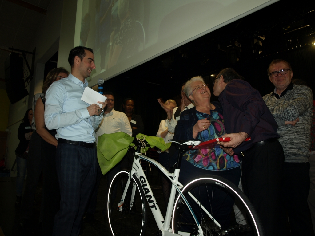 Échange entre participants pendant la remise d’un cadeau, devant le vélo.