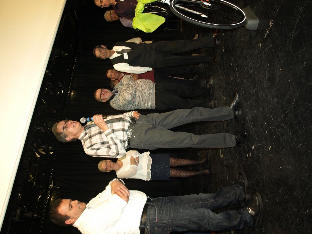 Un participant en chemise à carreaux parle au micro devant le groupe.