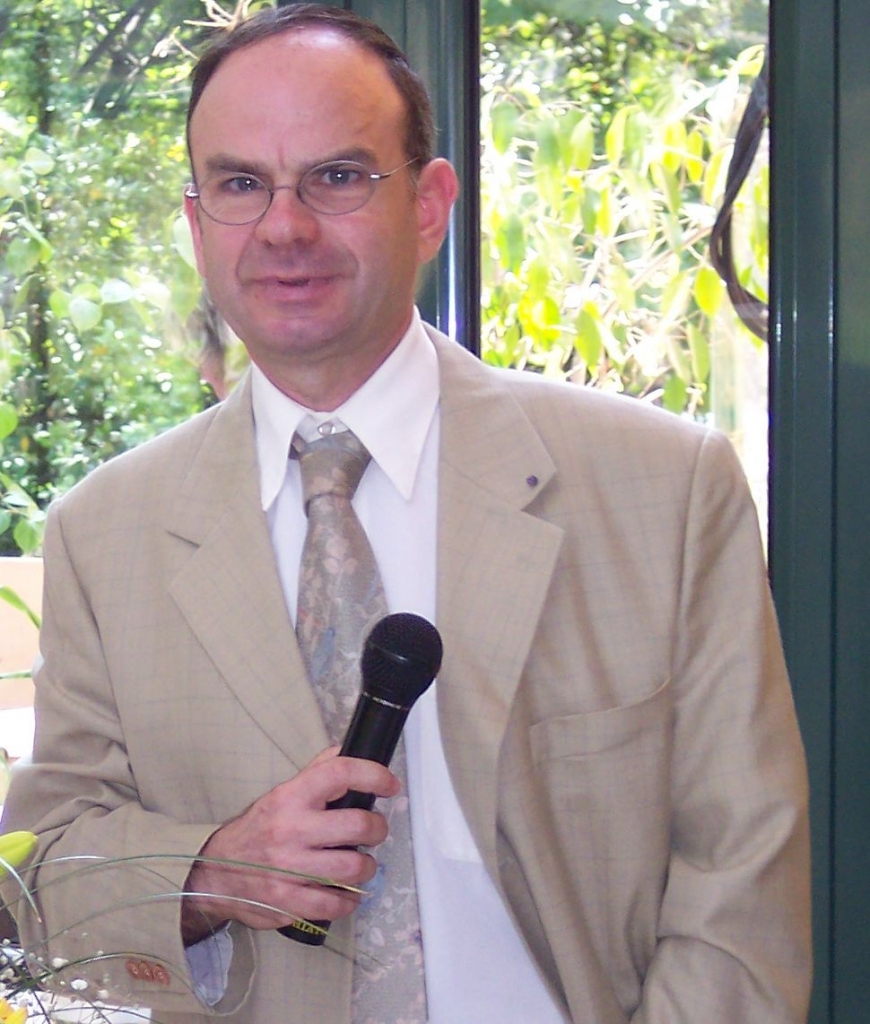 Portrait d’un homme en costume clair tenant un microphone.