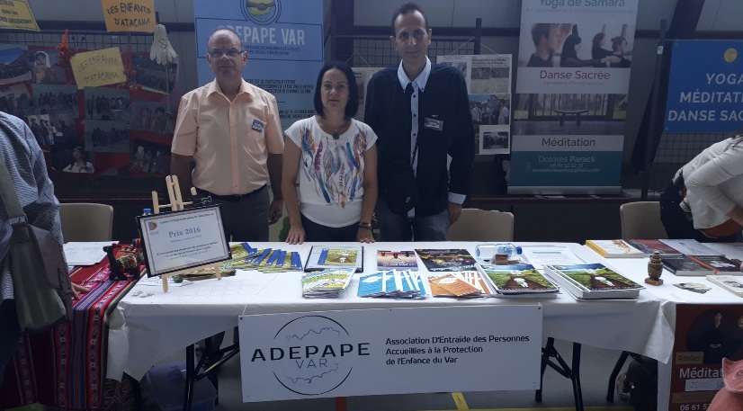 Trois personnes derrière un stand ADEPAPE couvert de brochures.