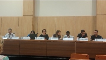 Intervenants assis derrière une longue table de réunion avec leurs porte-noms.