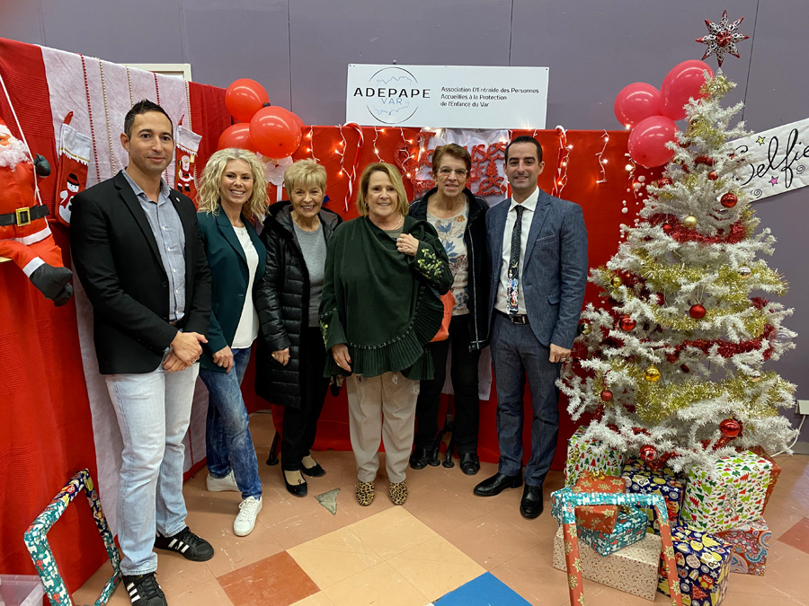 Groupe de participants devant le sapin blanc et le décor rouge de l’arbre de Noël 2019.