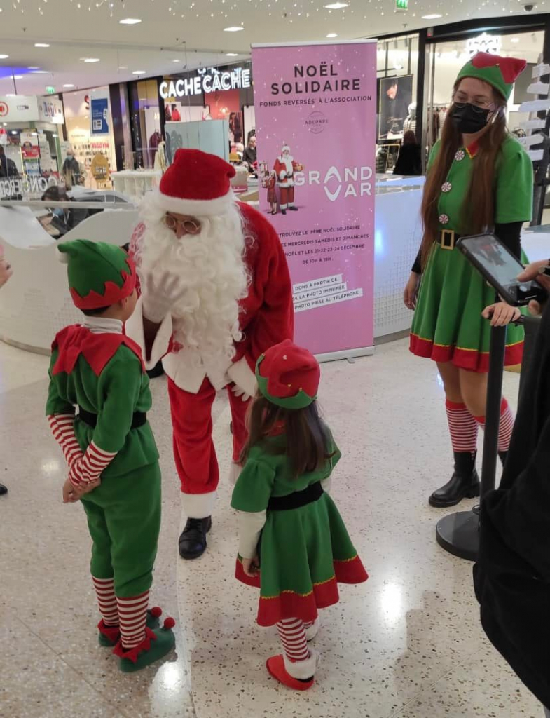 Le Père Noël rencontre des enfants costumés en lutins dans la galerie commerciale.