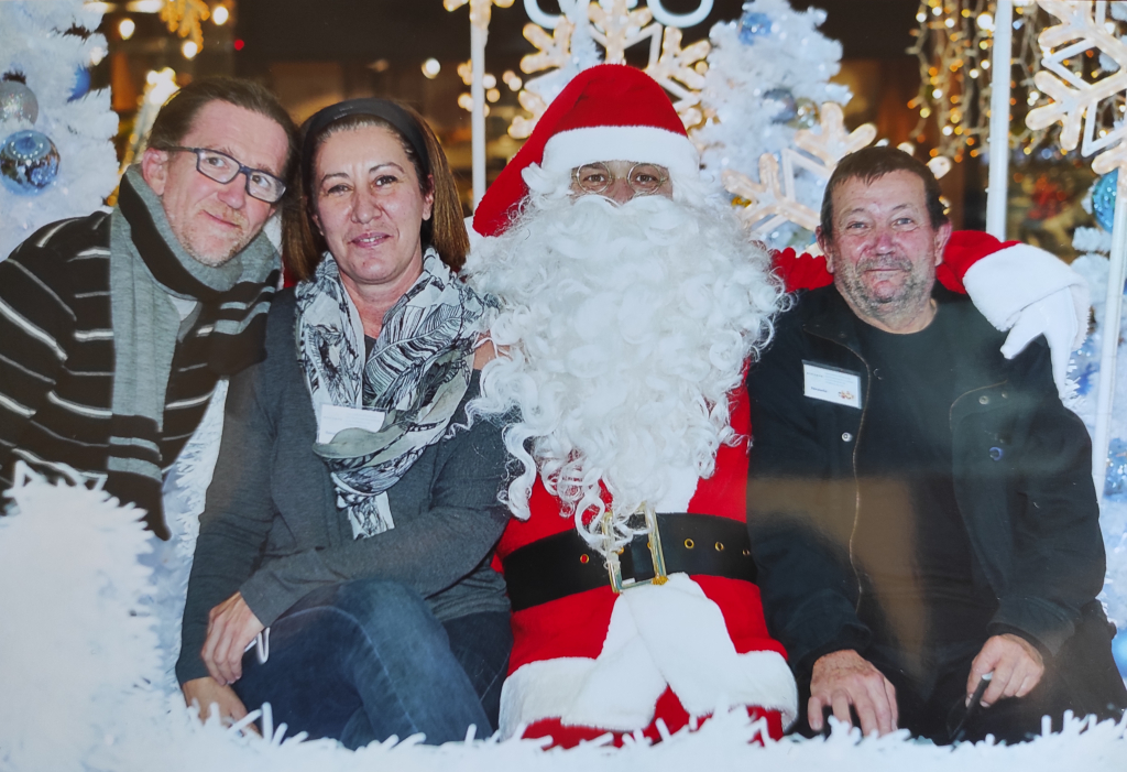 Trois participants posent avec le Père Noël dans le décor de Grand Var.