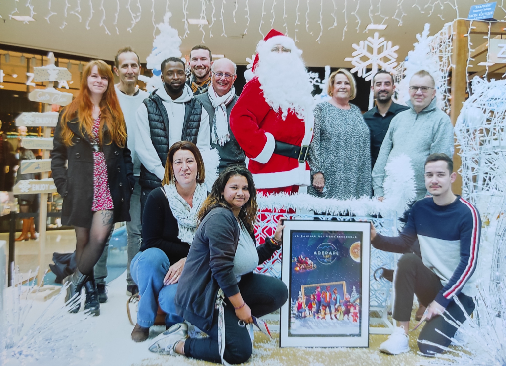 Photo de groupe autour du Père Noël, avec une photographie encadrée au premier plan.