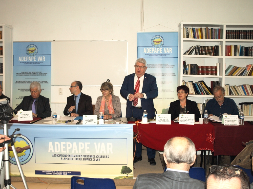 Un intervenant debout s’adresse au public depuis la table de l’assemblée générale 2016.