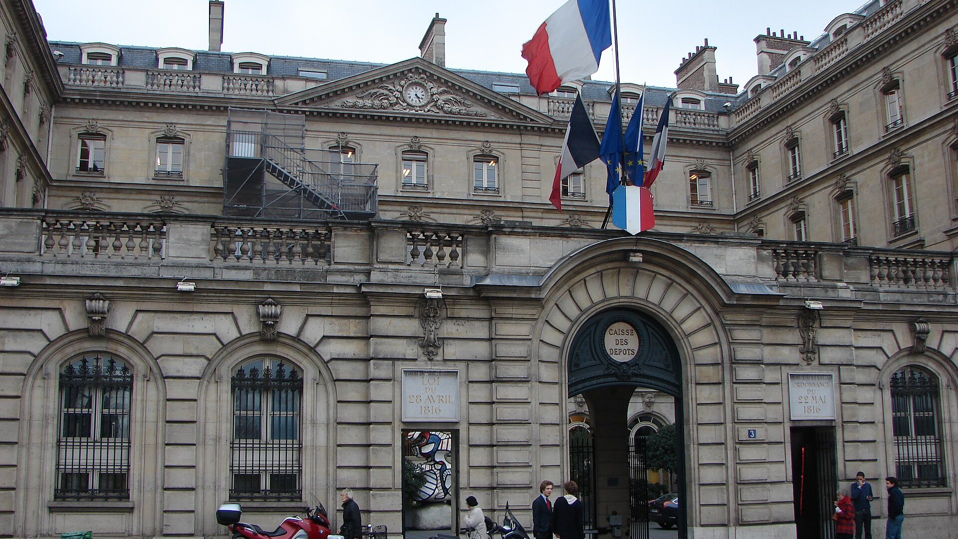 Façade du siège de la Caisse des dépôts, avec trois drapeaux au-dessus de l’entrée.