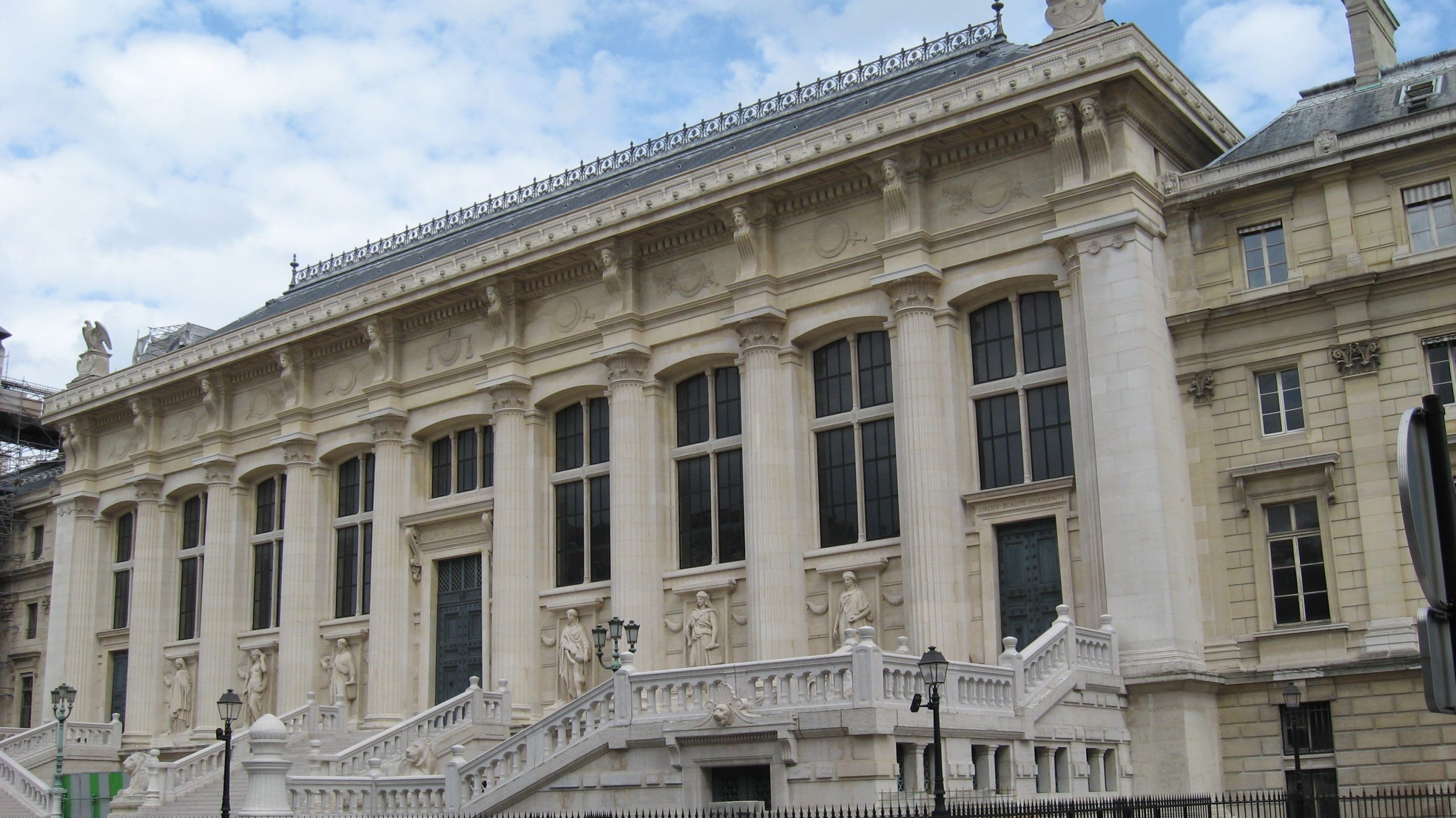 Façade en pierre du Palais de justice de Paris, avec ses colonnes et son grand escalier.