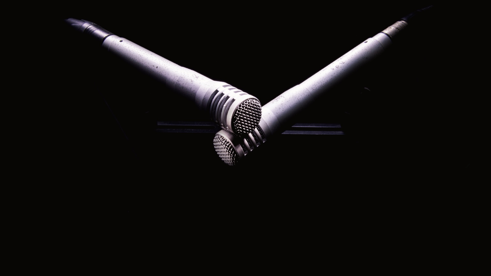 Trois microphones de studio éclairés sur un fond noir