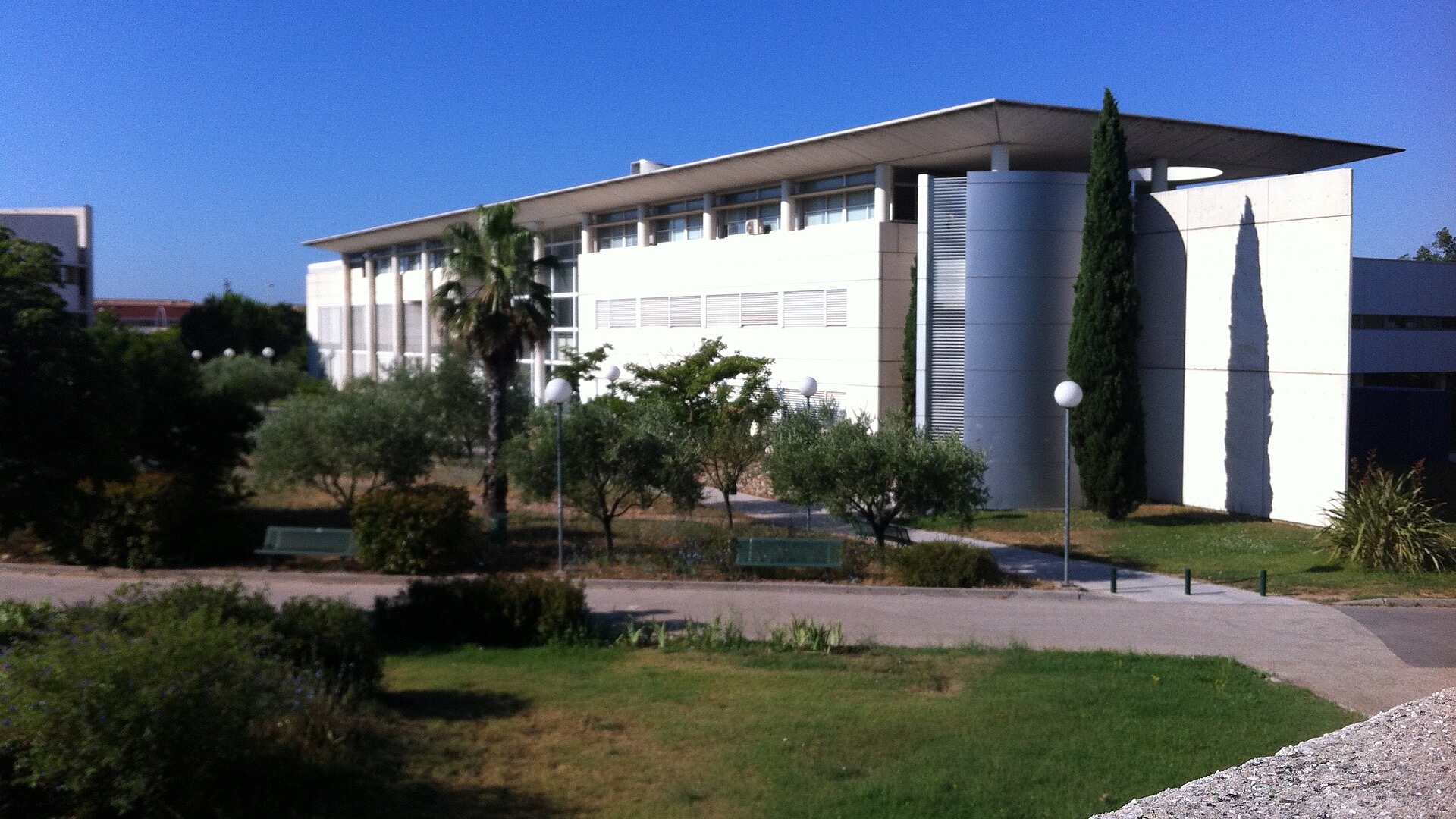 Un bâtiment universitaire entouré de pelouses et d’arbres.