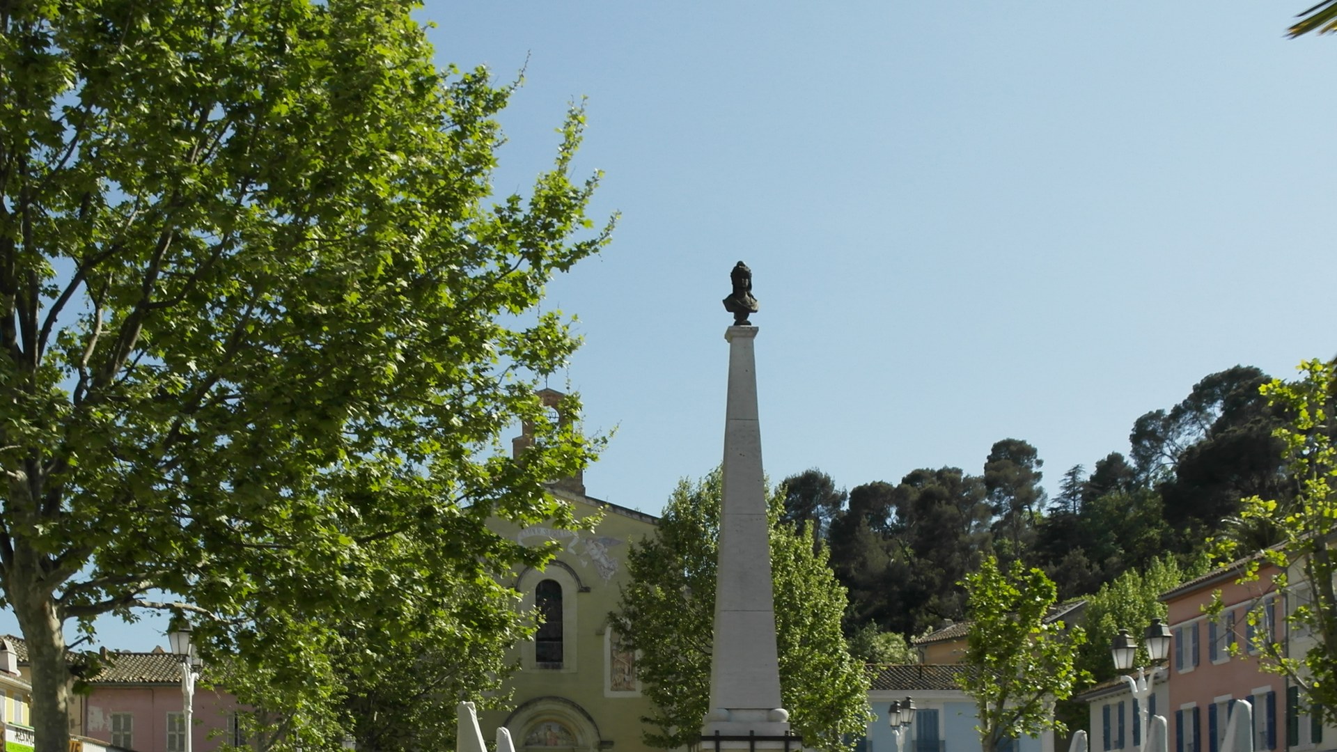 La place centrale du Pradet, dans le Var, un jour ensoleillé : l'église, le monument aux morts et les platanes.