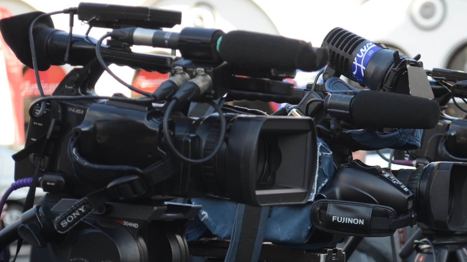 Deux caméras vidéo professionnelles équipées de micros, en train de filmer un événement en extérieur.