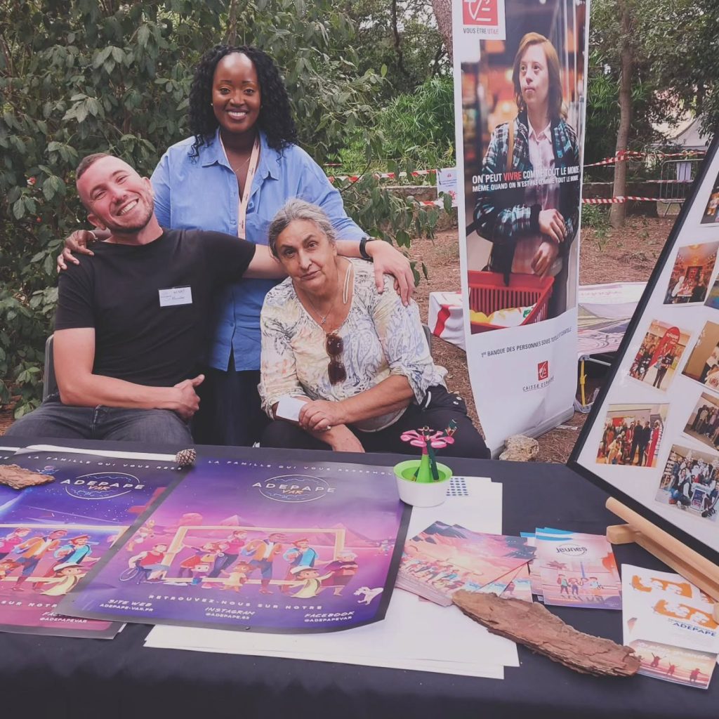 Trois personnes au stand de l’ADEPAPE Var, avec des documents et un panneau de photographies.