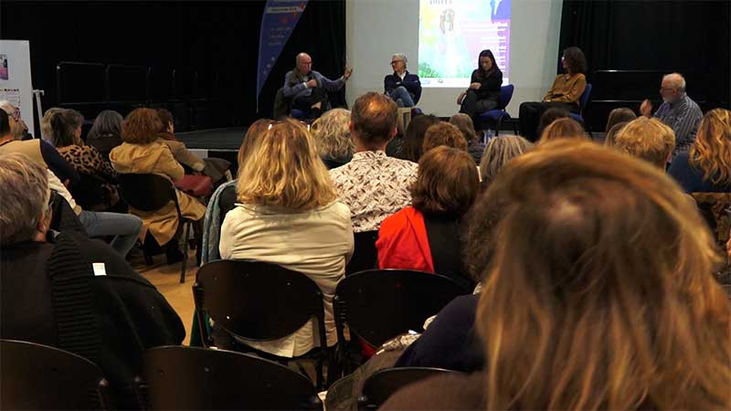 Le public et les intervenants réunis dans un auditorium.